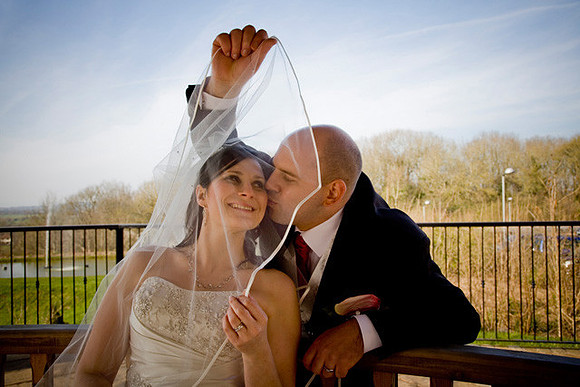 Groom kisses the bride beneath the wedding veil